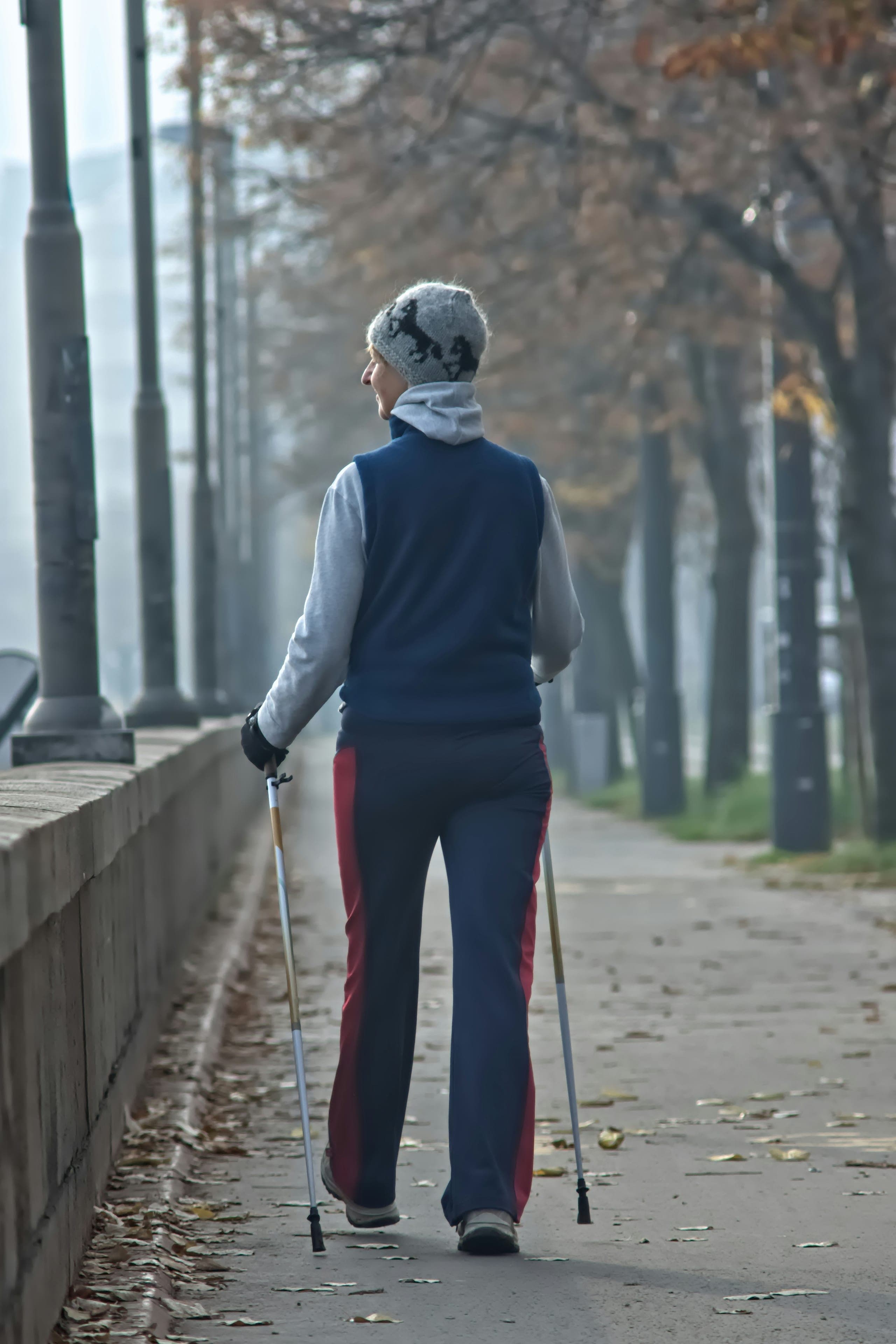 A woman walking with poles on a tree-lined path